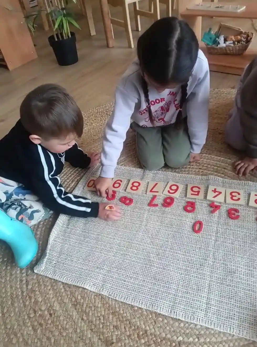 An educator sharing a practical life pouring activity with two toddlers at Montessori Home Early Learning Shepparton